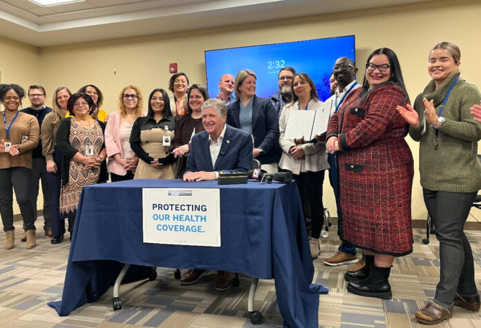El gobernador McKee acompañado por socios del sector salud mientras firma una orden ejecutiva para reducir las primas de HSRI para 20 mil clientes.