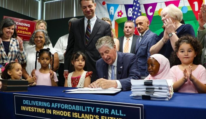 El gobernador McKee, acompañado por legisladores estatales, activistas y niños en Children's Friend, durante la firmar del presupuesto del año fiscal 2027.